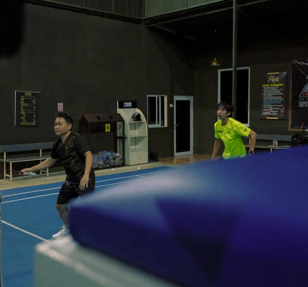 force-free training — Two men play badminton on an indoor court